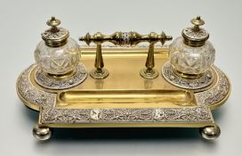A late 19th century brass desk standish, the rectangular platform on bun feet with part-bowed
