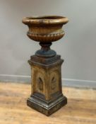 A fire clay brown speckled glaze urn and pedestal of Classical form, the pedestal with arch and