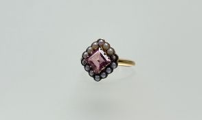 An Edwardian 18ct gold ring set cushion cut pink topaz within a surround of fourteen seed pearls.