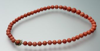 A graduated strand of pink coral beads with 18ct gold circular clasp also set with coral beads