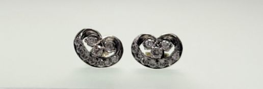An Edwardian pair of white metal stud earrings set three old mine-cut stones within a diamond