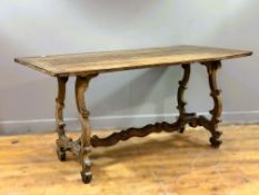 A late 19thc/early 20thc Iberian light oak trestle table with plank top on elaborate scroll supports