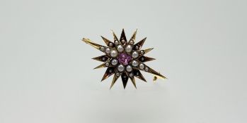 An Edwardian yellow metal starburst brooch set oval pink topaz within a double row of seed pearls: