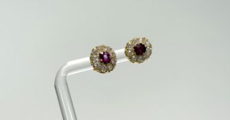 A pair of yellow metal stud earrings set oval enhanced ruby approximately 0.3ct within a surround of