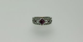 An 18ct white gold ring set four caibre cut, enhanced rubies in a diamond-shaped setting flanked