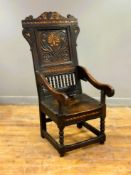 A 16th/17th century inlaid oak wainscot open armchair with arched scrolling crest rail and inset