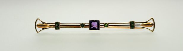 A 15ct gold Egyptian Revival bar brooch set central amethyst in millegrain setting flanked by a