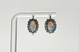 A pair of yellow metal earrings set oval fire opals within a surround of fourteen faceted round