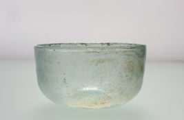 A pale green glass bowl, possibly Roman, c. 2nd to 4th century AD, hemispherical, with
