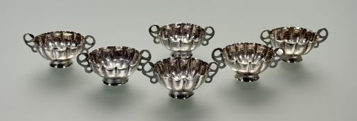 A set of six Greek white metal twin-handled cups, each bowl of scalloped form, with pierced handles,