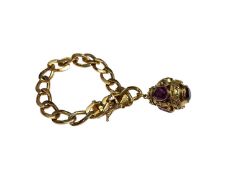 Continental yellow metal flat curb link bracelet with a yellow metal egg shaped pendant set with syn