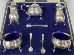 CASED GEORGE V SILVER FIVE PIECE CRUET SET of plain circular form, with blue glass liners and