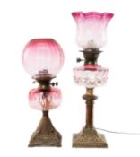 TWO CRANBERRY GLASS & BRASS OIL LAMPS, both with moulded reservoirs, largest 60cms (h) Provenance: