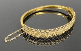15CT HOLLOW GOLD BANGLE, filigree decoration to upper half, with safety chain, 60 x 50mms