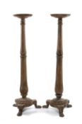 PAIR OF CARVED OAK TORCHÈRES, fluted baluster columns to tripod bases, on lion's paw feet, 135cms (