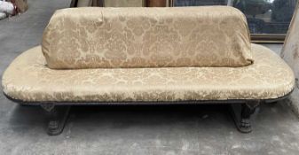 REGENCY STYLE EBONISED OVAL SOCIABLE SETTEE, padded back and all around seat, on carved frame and