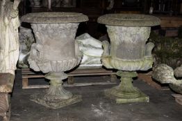 LARGE PAIR OF RECONSTITUTED STONE URNS, everted rims above grape vine ornament, gadrooned bases, and