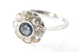 WHITE METAL SAPPHIRE & DIAMOND CLUSTER RING, central sapphire within border of eight round cut