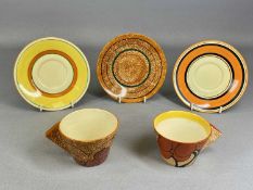 TWO CLARICE CLIFF BIZARRE CAFÉ AU LAIT TEACUPS, 'Blue Autumn' and 'Red Autumn', with three saucers
