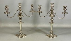 PAIR OF ORNATE PLATED THREE-BRANCH CANDELABRA, with floral and scroll embossed decoration, 42cms (h)