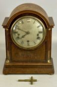 EDWARDIAN OAK CASED MANTEL CLOCK with arched top, silvered dial signed 'Finnigans of Manchester'