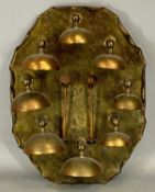UNUSUAL SET OF SERVANT'S BELLS, eight oxidised metal bells mounted on an oval shaped brass shield,