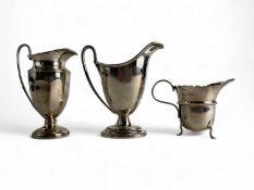 THREE GEORGE V SILVER CREAM JUGS, one helmet shaped by Walker & Hall, Sheffield 1913, 12.5cms (h),