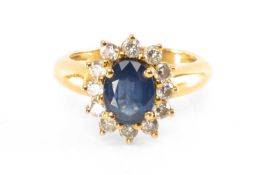 YELLOW METAL SAPPHIRE & DIAMOND CLUSTER RING, the oval cut sapphire (8 x 6mms) within border of