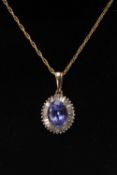 9K GOLD TANZANITE & DIAMOND PENDANT, the oval-cut tanzanite measuring 1.65cts, on yellow metal chain