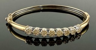 9CT GOLD & DIAMOND BANGLE, eight flower heads inset with tiny round-cut diamonds set in white
