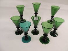SEVEN ANTIQUE GREEN GLASS WINE GLASSES, with knopped stems and turned circular bases, together