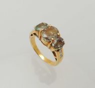 ALEXANDRITE THREE-STONE RING, central oval cut stone approx. 8 x 7mms, shoulders channel set with