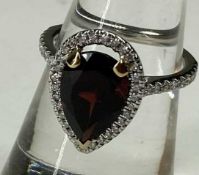GARNET & DIAMOND HALO RING, the pear cut garnet approx. 3.8cts, bordered with small brilliants,