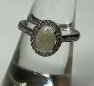 OPAL & DIAMOND HALO RING, the opal approx. 7 x 5mms, bordered with small brilliants, the shoulders
