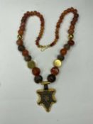 MUSÉON ART ANTIQUE CORNELIAN BEADED NECKLACE, supporting a Roman bronze pendant, newly mounted in