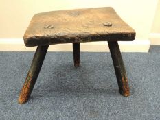 LARGE RUSTIC ELM MILKING STOOL, 18th century or earlier, with rectangular seat and three hewn