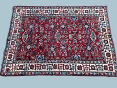 WITHDRAWN FROM AUCTION - IRANIAN HERIZ STYLE WOOLLEN CARPET, deep red field, fawn and blue border,