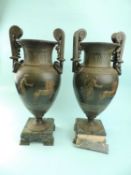 AFTER THE ANTIQUE PAIR OF ROMAN-STYLE METAL URNS, decorated with chariots, on square marble bases,
