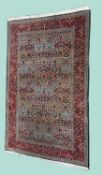 TURKISH HEREKE WOOLLEN RUG with blue field, all over floral design within a red foliate border,