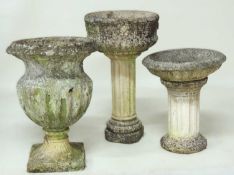 TWO WEATHERED RECONSTITUTED STONE PEDESTAL GARDEN URNS, tallest 68cms (h); together with a weathered