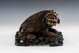 CARVED HARDWOOD FIGURE OF A KARASHISHI, with glass eyes, and bone teeth, on stained naturalistic