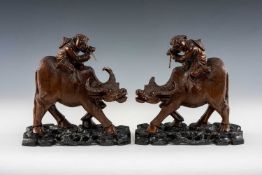 PAIR OF CHINESE HARDWOOD 'BOY ON BUFFALO' CARVINGS, animals with inset glass eyes, on ebonised
