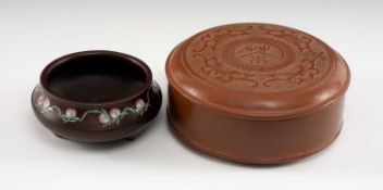TWO CHINESE YIXING POTTERY CONTAINERS, comprising a fifteen-peach famille rose enamelled tripod