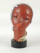 GOLDSCHEIDER ART DECO BUST of a stylised lady, cream and green glaze, on ebonised wood drum base