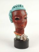 GOLDSCHEIDER ART DECO BUST of a stylised lady, turquoise and orange glaze, on wooden drum base