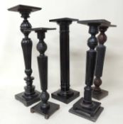 FOUR EBONISED WOODEN TORCHÈRES, and a similar torchère, including ball and baluster example,