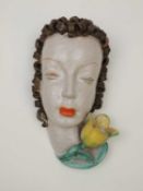 GOLDSCHEIDER ART DECO WALL MASK of a lady with brown curly hair, yellow tulip to base, black printed