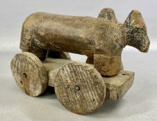 CHILD'S PRIMITIVE WOODEN PULL-ALONG TOY, in the form of a bull, on four-wheeled stand with faded