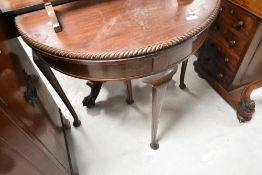 An early 20th Century mahogany demi lune fold over card table having gadrooned edge and cabriole