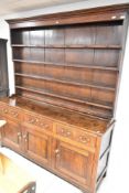 A period oak dresser , having delft rack and three frieze drawers over triple cupboard, on bracket